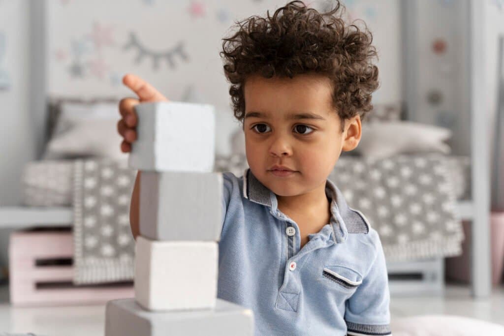 A young child focused on building blocks at home, illustrating what is autism and hyper-focus in a homeschooling environment.